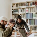 Grupo de personas trabajando juntas alrededor de una computadora portátil